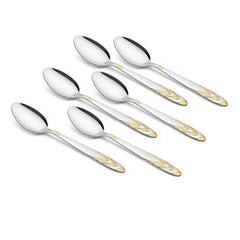 Six FNS stainless steel dessert spoons with elegant gold-accented handles arranged in display formation on white background