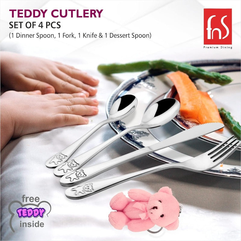 Children’s cutlery set with engraved teddy bears placed beside a meal plate and toddler’s hands.