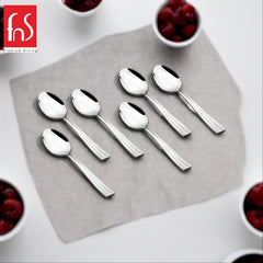 Six polished stainless steel Venice teaspoons with ribbed handles arranged on gray square plate, surrounded by white bowls of red berries at corners, FnS Premium Dining logo visible