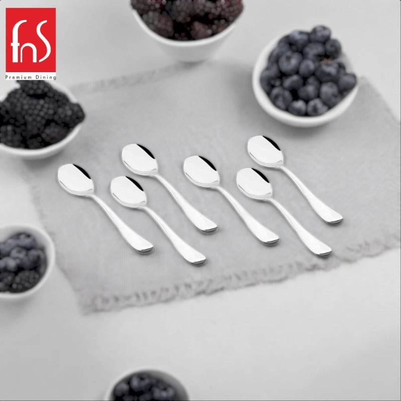Six polished stainless steel teaspoons arranged on a gray square plate with white bowls of red berries in the corners, FnS Premium Dining logo in top left
