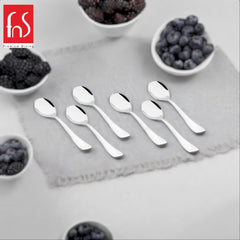 Six polished stainless steel teaspoons arranged on a gray square plate with white bowls of red berries in the corners, FnS Premium Dining logo in top left