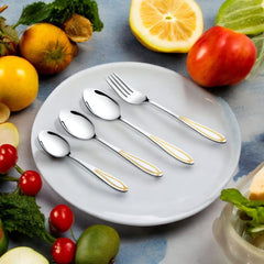 Fork and spoons with gold-accented handles placed on a white plate surrounded by colorful fruits and vegetables.
