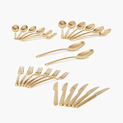 Full gold cutlery set spread out neatly, including spoons, forks, and knives in matching finish.