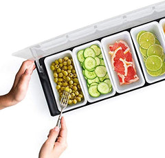 Hands using fork to access condiment caddy with six sections containing green olives, cucumber slices, grapefruit, and lime slices