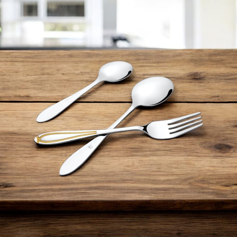 Cutlery trio placed on rustic wooden surface, featuring one piece with gold inlay on handle.