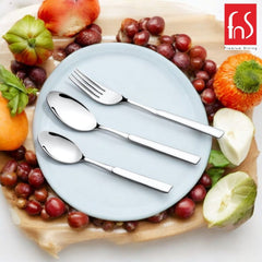 Modern spoon, fork, and teaspoon on ceramic plate surrounded by vibrant fruit and rustic platter.