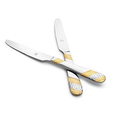 Two crossed stainless steel dinner knives with elegant gold and silver patterned handles on clean white background for product display.