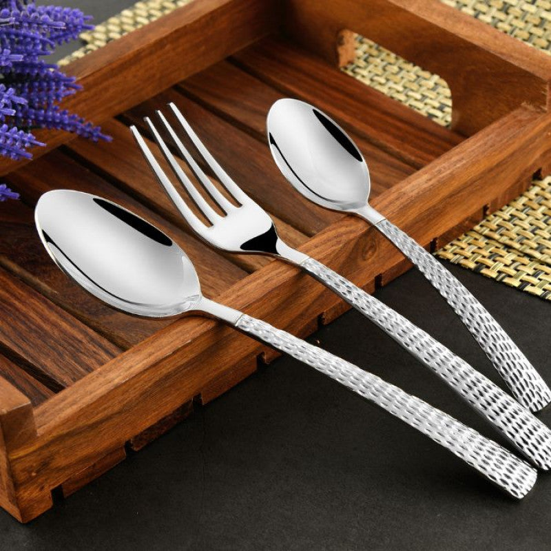 Elegant spoon and fork set with hammered steel handles resting on a rustic wooden serving tray.