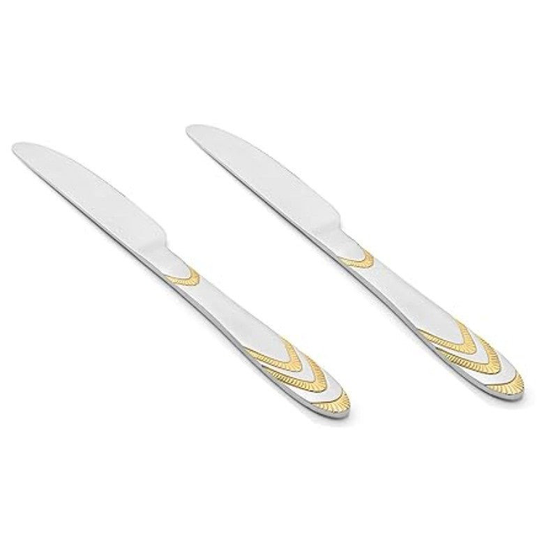 Pair of stainless steel Magna dinner knives with decorative gold chevron handles displayed diagonally on clean white background for flatware collection.