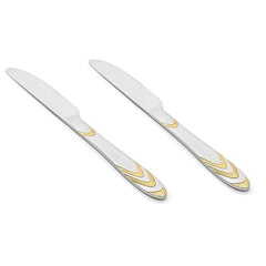Pair of stainless steel Magna dinner knives with decorative gold chevron handles displayed diagonally on clean white background for flatware collection.