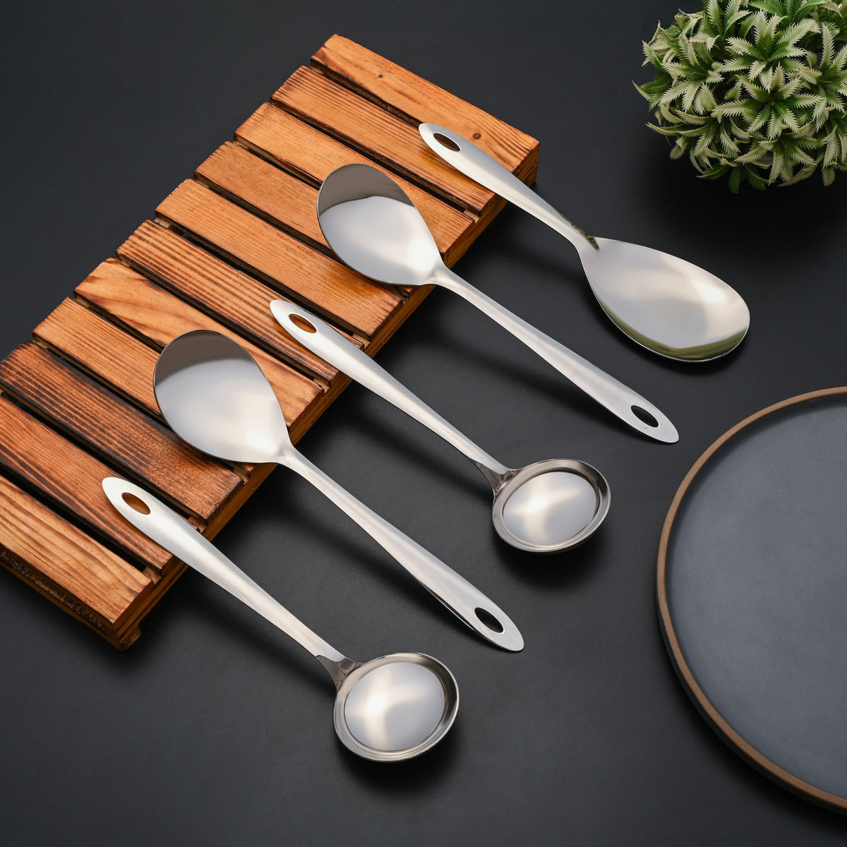 Montavo Amazon 5-piece stainless steel serving spoons on wooden tray with ceramic plate, showcasing mirror polish finish and ergonomic oval handle design.