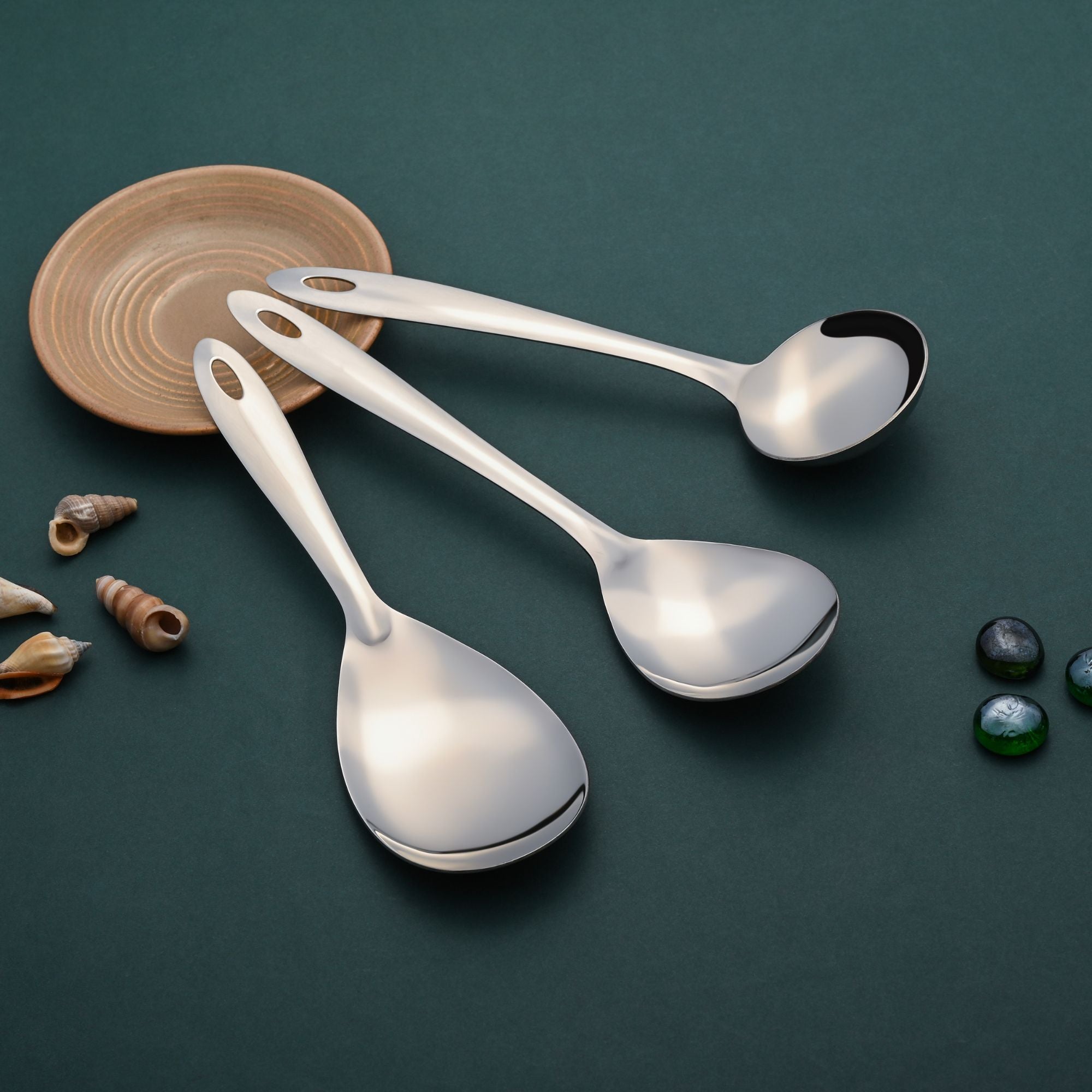 Montavo Amazon serving tools 3-piece set arranged on teal surface with natural wooden bowl, seashells, and pebbles for elegant lifestyle presentation