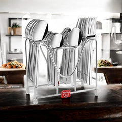 Stainless steel cutlery set in a modern rack displayed on a kitchen counter with food background.