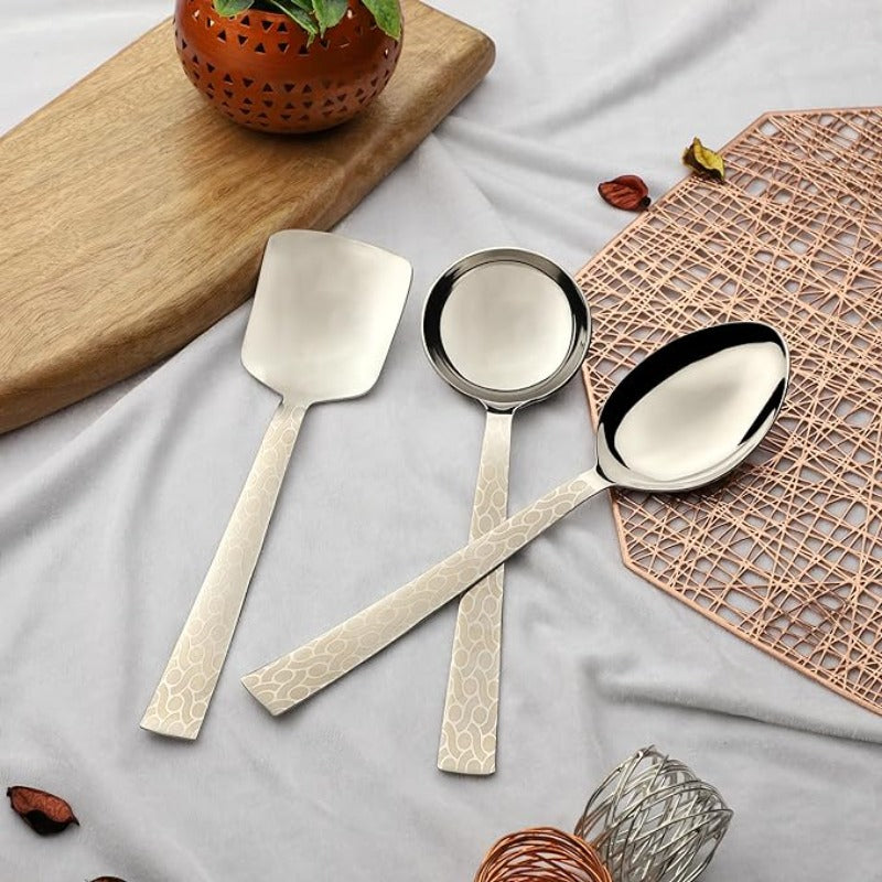 Montavo by FNS Pacific 3-piece serving set with laser engraved crackle pattern handles displayed on white cloth with wooden board and copper mat