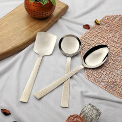 Montavo by FNS Pacific 3-piece serving set with laser engraved crackle pattern handles displayed on white cloth with wooden board and copper mat