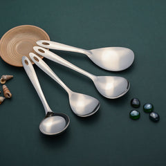 Montavo serving spoons kitchen essentials set displayed on teal background with decorative wooden coaster and accent elements.