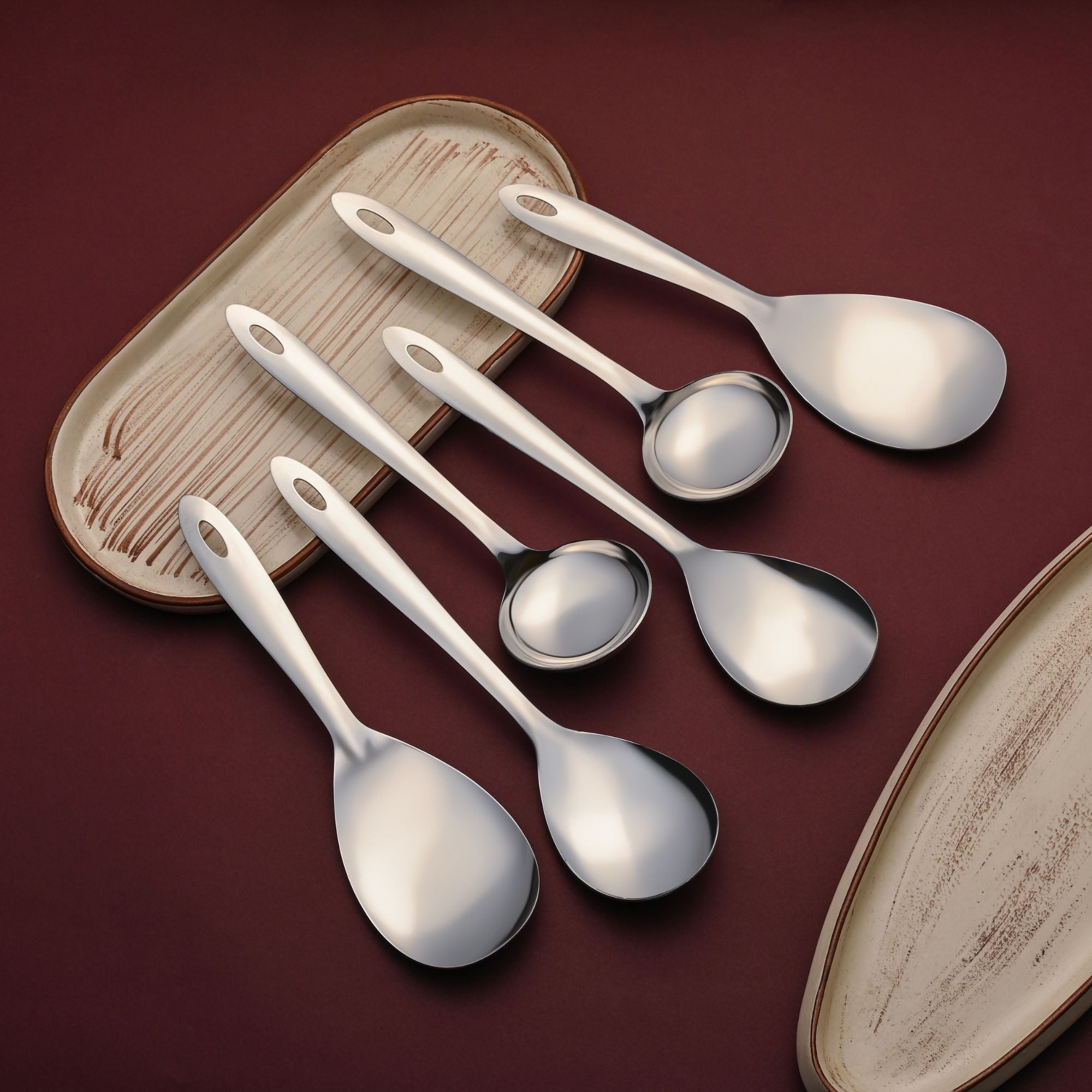 Montavo stainless steel serving spoons elegantly arranged on rustic wooden tray with decorative plate