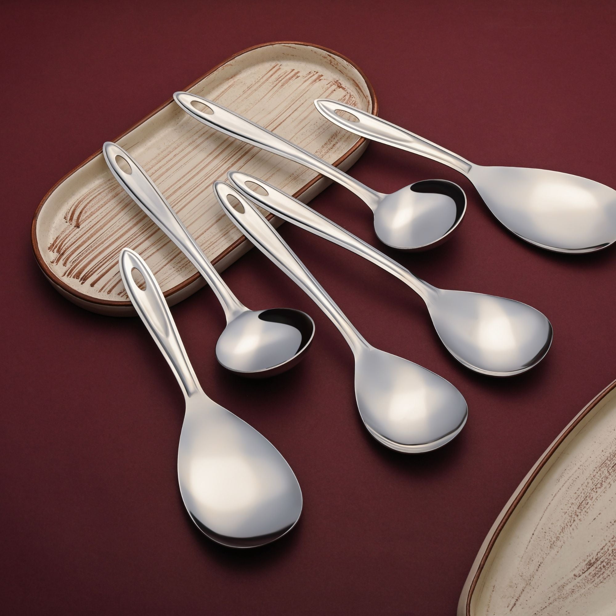 Montavo Trinity 6-piece serving utensil set arranged on rustic wooden tray with burgundy table setting showcasing premium stainless steel quality