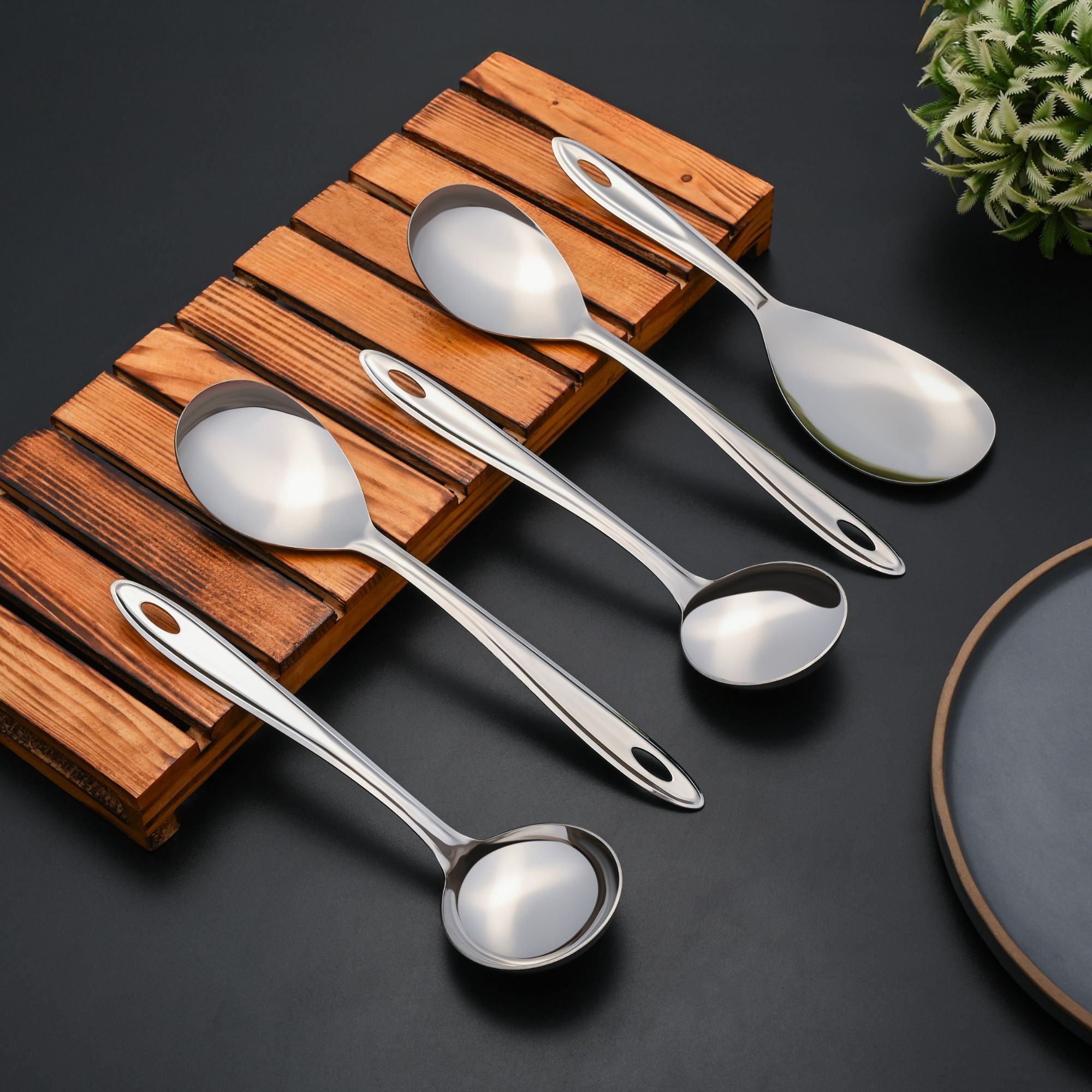 Montavo Trinity serving spoons displayed on wooden tray with dark plate, highlighting premium quality and elegant design for modern kitchens.