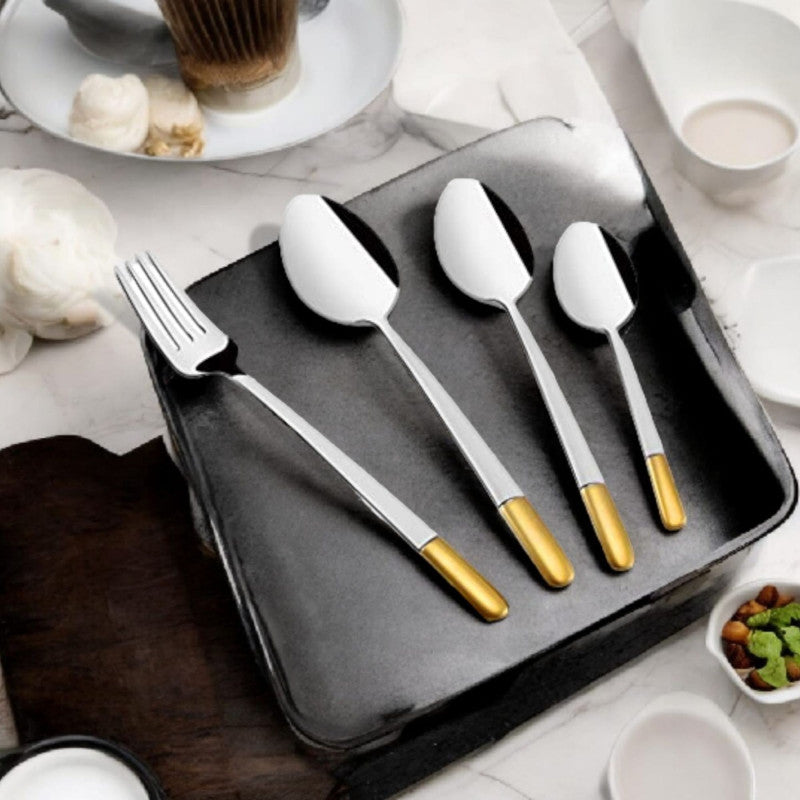 Sophisticated cutlery set with gold handles displayed elegantly on a black tray with coffee and snacks.