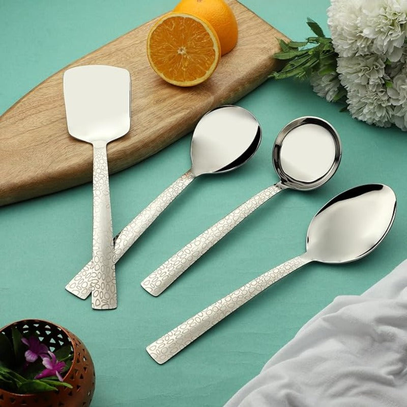 Pebble serving spoon set with 4 pieces featuring textured handles displayed on turquoise background with cutting board and oranges