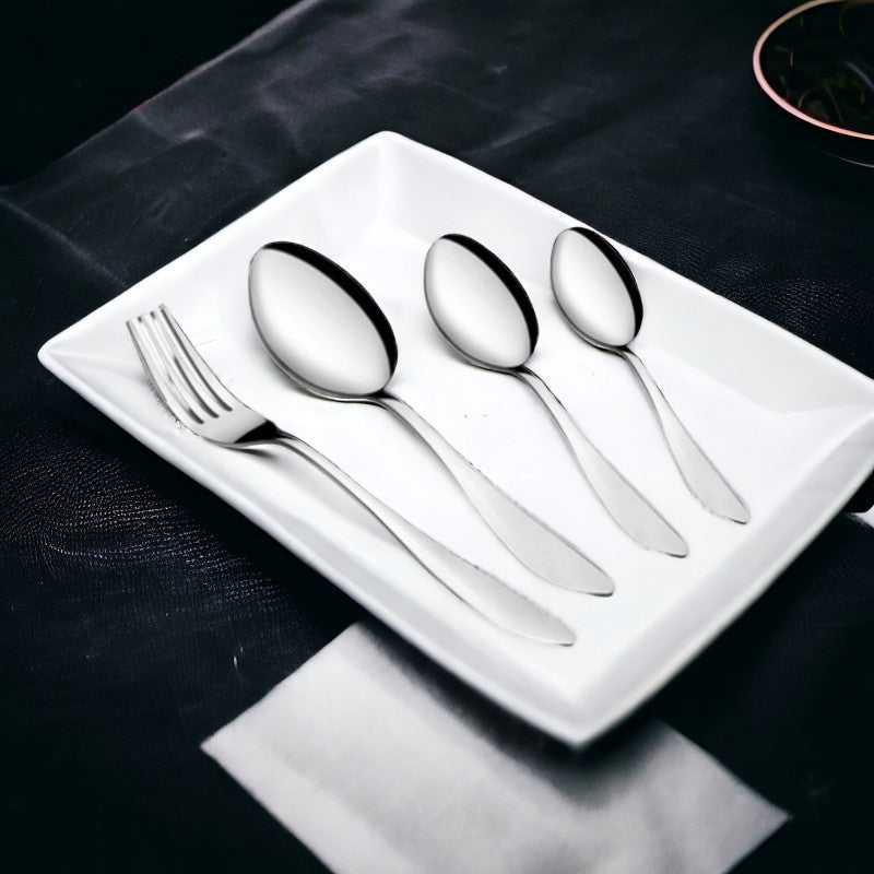 Four-piece cutlery set including fork and spoons arranged on white plate over dark tablecloth.
