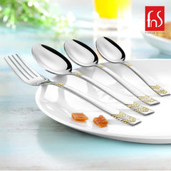 Silver cutlery with gold accents placed on white plate, showcasing reflective finish and elegant design.