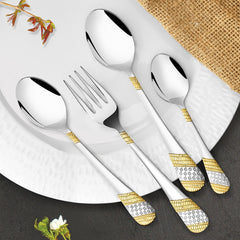 Stylish silver-gold flatware placed on white plate with rustic table setting and floral accents.