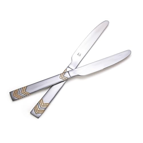 Two Raga dinner knives with gold chevron handles crossed artistically on white background, showcasing sleek stainless steel blades and decorative design.