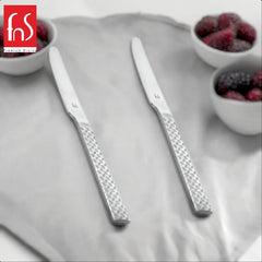 Two FnS Rhombo dinner knives with distinctive geometric diamond-pattern textured handles on white plate beside small bowls with berries.