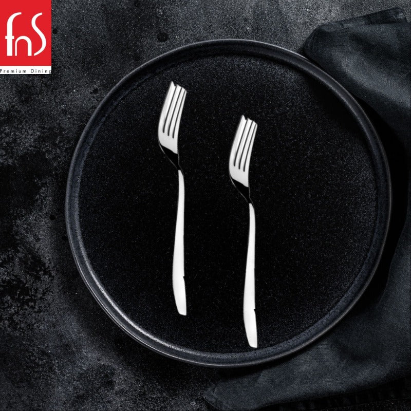 Two Rio stainless steel dinner forks displayed on black plate with dark textured background and black napkin