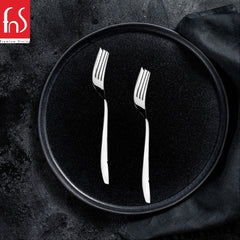 Two Rio stainless steel dinner forks displayed on black plate with dark textured background and black napkin