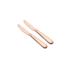 Two FnS Rosella rose gold dinner knives arranged diagonally, showcasing elegant curved handles and polished finish against clean white background.