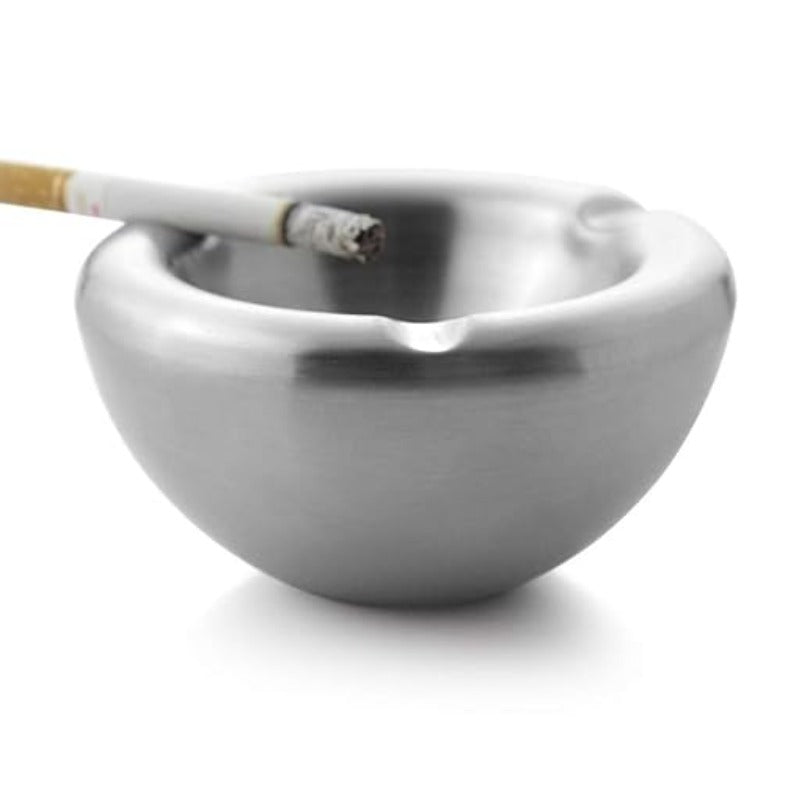 Stainless steel ashtray with lit cigarette resting on edge, close-up shot on white background