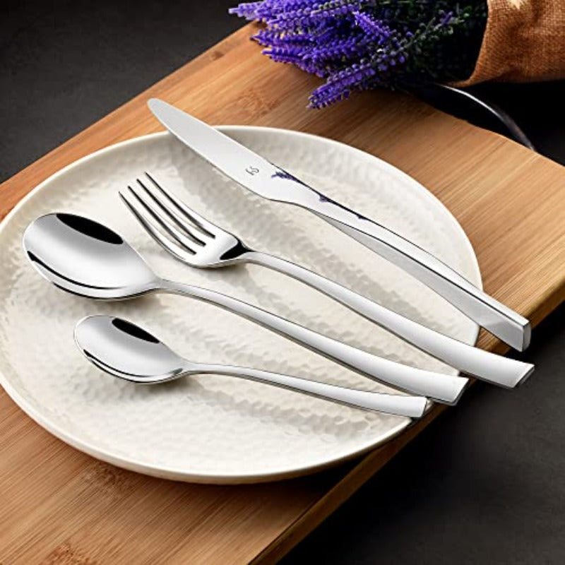 Elegant silver cutlery set with curved handles arranged on textured plate beside lavender on wood board.