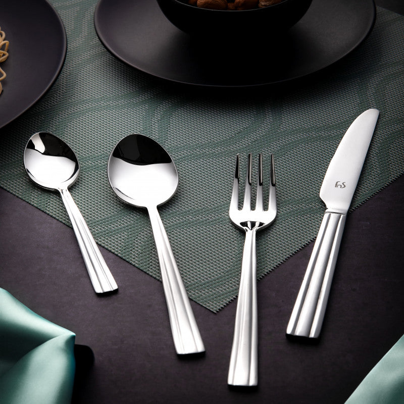 Elegant stainless steel cutlery set with fork, spoons, and knife placed on green textured placemat.