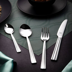 Elegant stainless steel cutlery set with fork, spoons, and knife placed on green textured placemat.