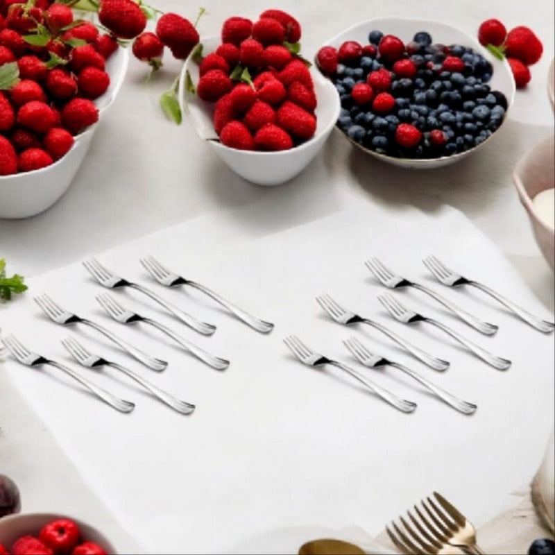 Fresh berries in bowls with arranged dinner forks on white tablecloth