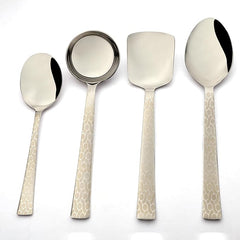 Four-piece Pacific serving utensil set with mirror-polished steel heads and decorative pebble-textured cream-colored handles