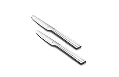 Pair of polished stainless steel dinner knives with sleek grooved handles on plain white background.