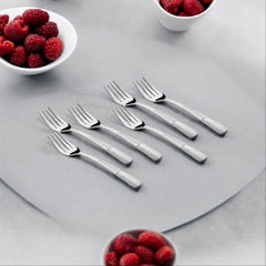 Six stainless steel dinner forks with textured handles arranged on gray surface with raspberry bowls
