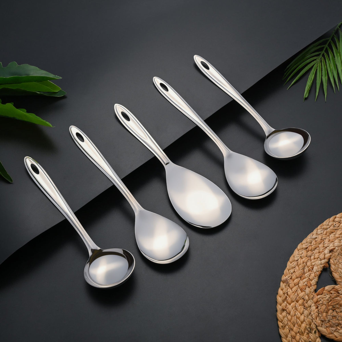 Trinity 5-piece serving spoon set arranged elegantly on dark background showcasing polished stainless steel finish and ergonomic handle design.