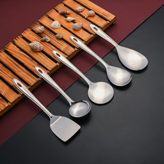 Trinity serving tools including spoons, ladle, and spatula arranged on wooden board with seashells and burgundy accent