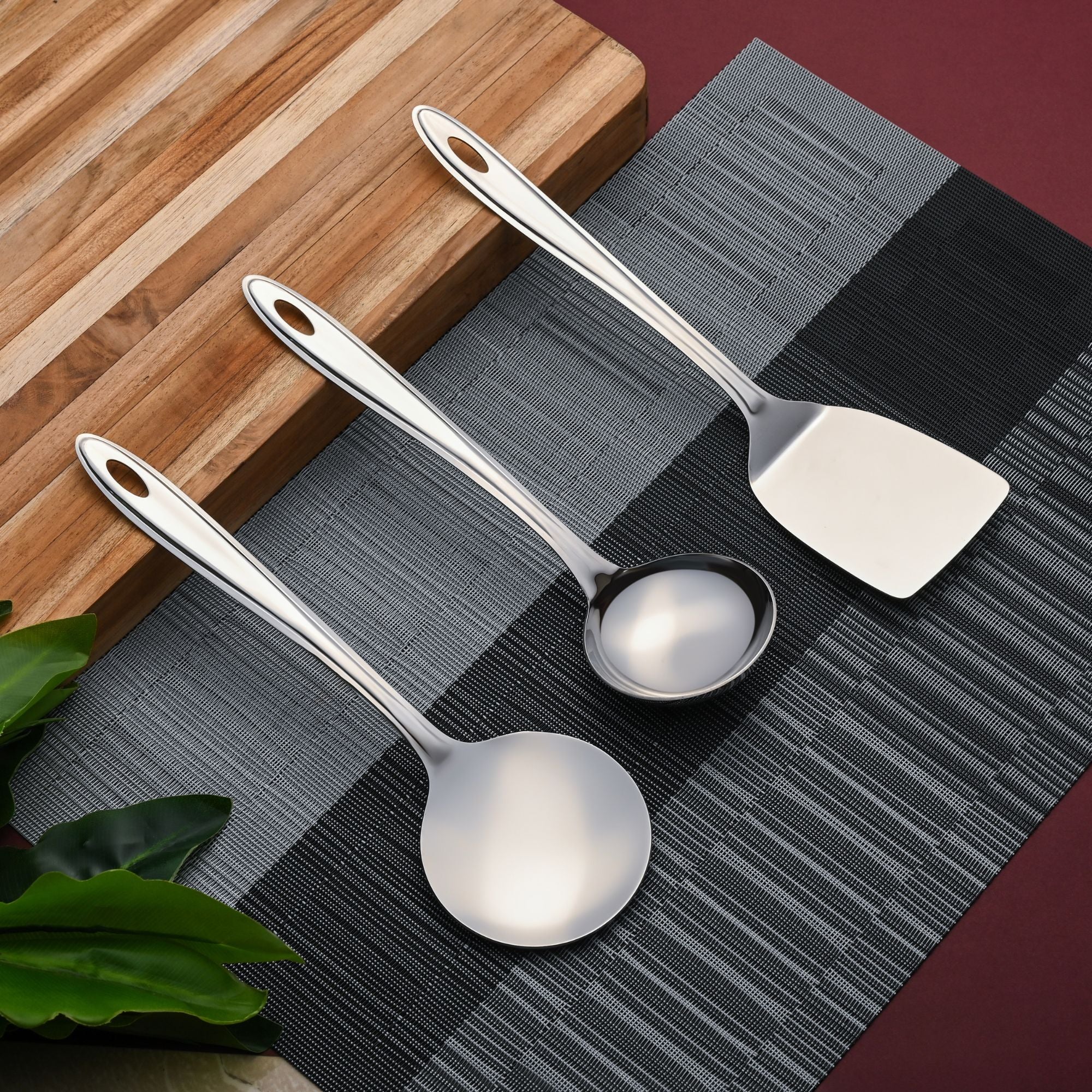 Trinity serving utensils arranged on gray placemat with wooden cutting board in modern kitchen lifestyle setting