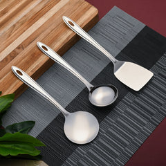 Trinity serving utensils arranged on gray placemat with wooden cutting board in modern kitchen lifestyle setting