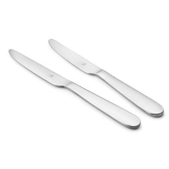 Two stainless steel butter knives with ergonomic curved handles and serrated edges arranged diagonally on white background showcasing sleek minimalist design.